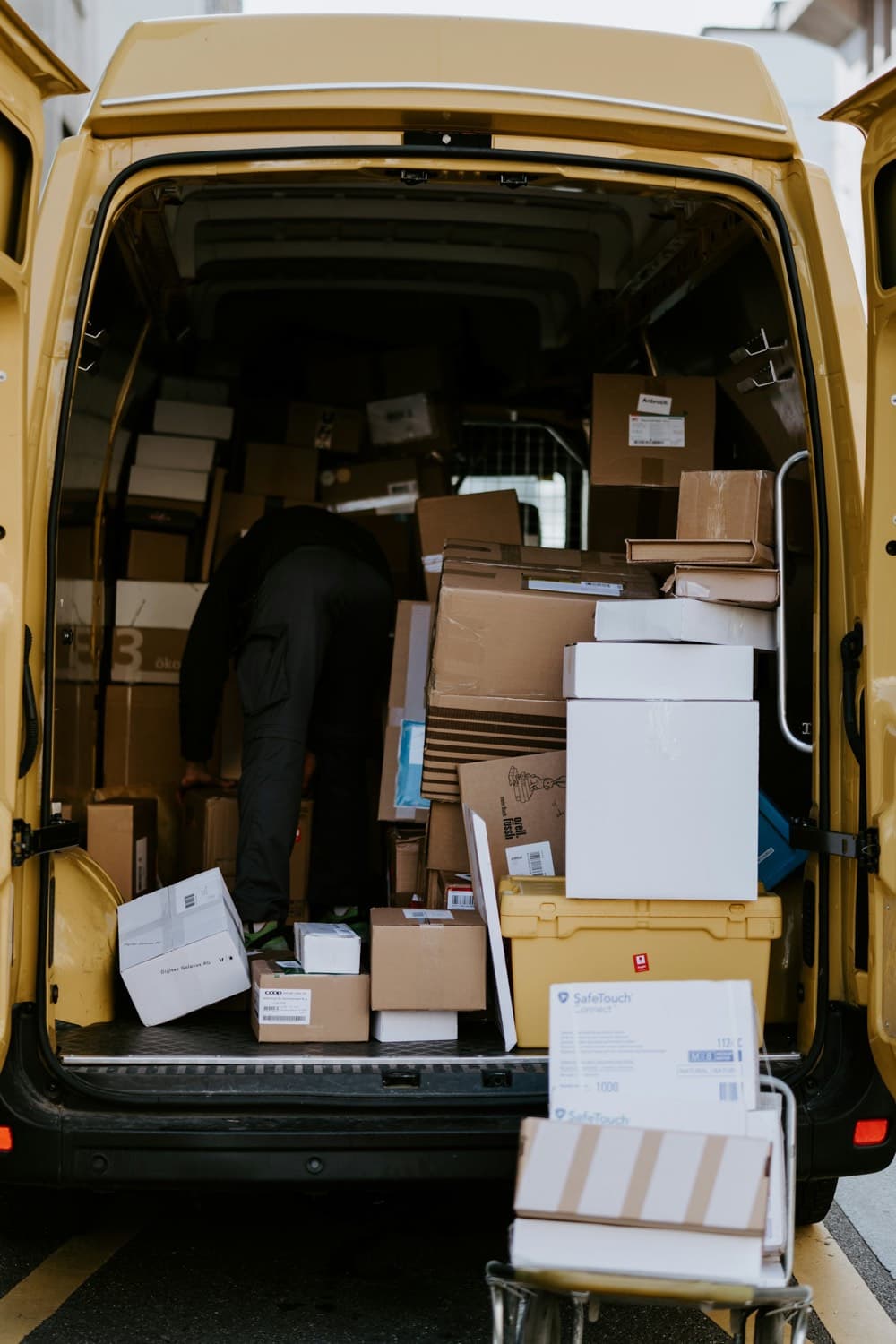 Un coursier charge des cartons à l’arrière d’une camionnette de livraison